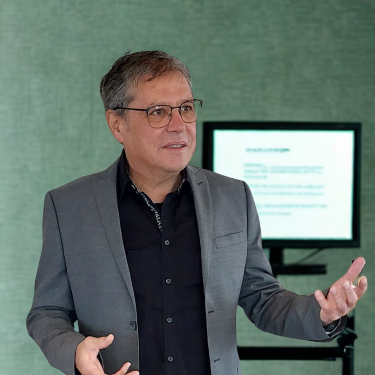 Mann spricht vor großem Publikum in einem modernen Veranstaltungsort.